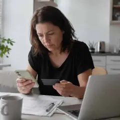 Kobieta z kartą płatniczą i telefonem zastanawia się, ile czasu na zwrot ma zamówiony towar.