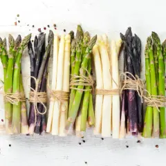 Mazzi di asparagi verdi, bianchi e viola legati con spago. Ideali per scoprire il giusto tempo cottura asparagi.