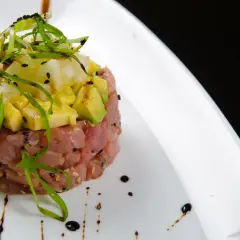 Deliziosa tartare di tonno con avocado e ananas, guarnita con erba cipollina e semi di sesamo nero.
