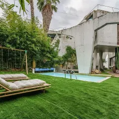 El jardín de la casa Sebastián San José invita al relax con tumbonas, piscina y columpios.