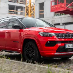 Czerwony Jeep Compass na tle budowy. Elegancki SUV gotowy na miejskie wyzwania.