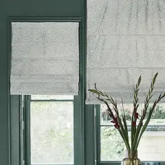 Tende a pacchetto grigie scintillanti fino al davanzale, accanto a una tenda con pennellate astratte colorate.