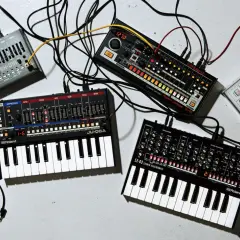 Ensemble de matériel pour composer musique électronique : synthétiseurs, boîtes à rythmes et câbles.