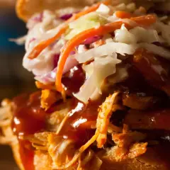Gros plan sur un sandwich gourmand : effiloché de porc savoureux, sauce barbecue onctueuse et salade de chou croquante. Un délice !