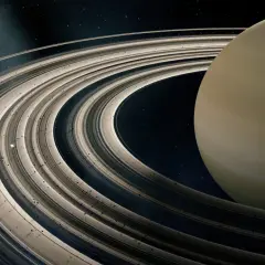 Majestatyczne pierścienie planet otaczają gazowego giganta. W oddali widać mały księżyc.