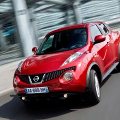 Czerwony Nissan Juke pędzi po drodze, jego dynamiczna sylwetka podkreślona przez ruch.