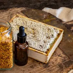 Słoik z pyłkiem pszczelim, buteleczka z kroplomierzem i plaster miodu. Naturalne składniki, które mogą posłużyć jako propolis lek.