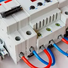 Ogranicznik przepięć T1+T2 chroni instalację przed przepięciami. Widoczne moduły z przewodami czerwonym i niebieskim.
