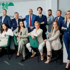 Grupa prawników w garniturach pozuje do zdjęcia w biurze.