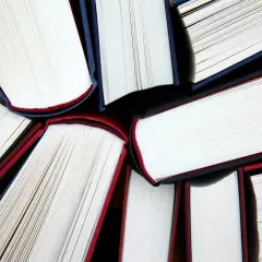 Zbliżenie na otwarte książki z białymi kartkami i czerwonymi oraz granatowymi okładkami.