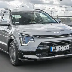 Szary Kia Niro w ruchu drogowym. Sprawdź atrakcyjną kia niro cena i wybierz swój nowy samochód.