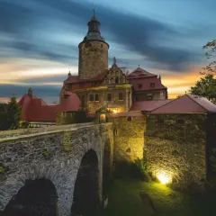 Zamek Czocha, gdzie jest, w blasku zachodzącego słońca, z kamiennym mostem i wieżą.