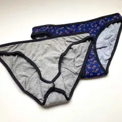 Two pairs of cotton underwear, one grey with a snap closure, the other blue floral. Perfect for a DIY period underwear project.