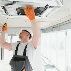 Técnico revisa unidad de aire acondicionado en el techo. Aprende como saber si un aire acondicionado tiene gas.