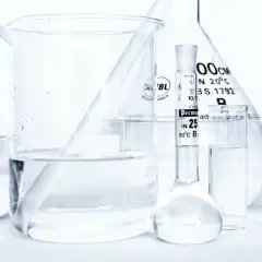 Laboratorium z naczyniami szklanymi, w tym zlewką z płynem i pipetą z oznaczeniem "caprylyl glycol".