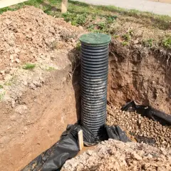 Wykop pod rów melioracyjny z rurą drenarską i żwirem. Jaka rura do rowu melioracyjnego? Ta karbowana, czarna rura z zieloną pokrywą jest gotowa do pracy.