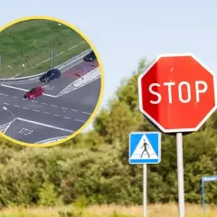 Czerwony samochód ignoruje znak STOP, ryzykując niezatrzymanie się na stopie. Obok znak przejścia dla pieszych.