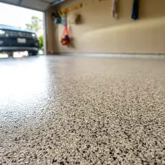 Glänzender, gesprenkelter garagenboden beschichten. Autos parken auf dem frisch beschichteten Boden.