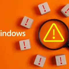 Windows-Logo, Lupe mit Warnsymbol, Holzklötze mit Ausrufezeichen. Ein Hinweis auf eine Systemprüfung wie chkdsk /scan.
