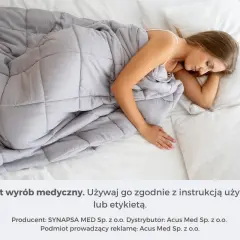 Kobieta śpi pod szarą kołdrą obciążeniową. Dowiedz się, jak dobrać idealną kołdrę obciążeniową dla siebie.
