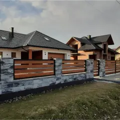 Nowoczesne ogrodzenie domu z betonowych bloczków i drewnianych desek. Świetny pomysł na ogrodzenie domu, który podkreśla jego styl.