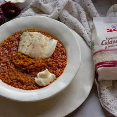 Un plato de caldero murciano con pescado y un toque de alioli, acompañado de arroz especial caldoso y pimientos secos.