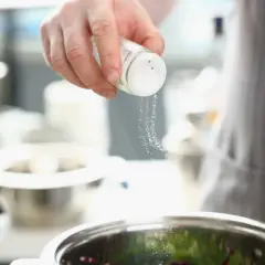 Une main saupoudre du sel dans un bol, ajoutant une touche de saveur à la cuisine.