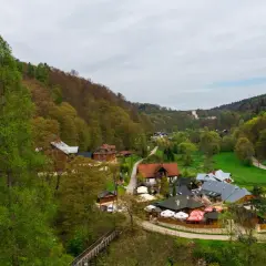 Malownicza dolina w okolicach Krakowa, z zabudowaniami i lasami.