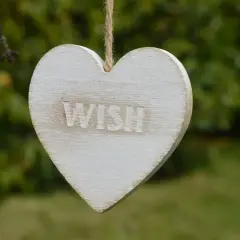 Drewniane serce z napisem "WISH" wisi na sznurku. Idealne na życzenia urodzinowe dla podróżnika, by spełniły się jego marzenia o dalekich wyprawach.