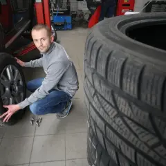 Mechanik sprawdza opony wielosezonowe, szukając najlepszych opinii przed sezonem.