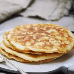 Stos puszystych, trzyskładnikowych placków bananowych na talerzu, obok srebrnego widelca. Idealne na śniadanie.