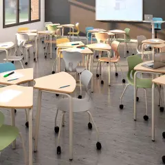 Aula moderna con mobiliario escolar innovador: mesas triangulares y sillas ergonómicas de colores vibrantes, listas para el aprendizaje.