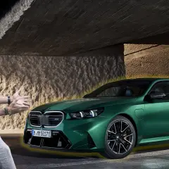 Mężczyzna z entuzjazmem prezentuje lśniące, zielone bmw g90 pod betonowym zadaszeniem.