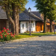 Urokliwa wieś, idealne miejsce, gdzie na wakacje w Polsce. Brukowana droga, kwitnące róże i tradycyjne chaty tworzą sielski klimat.