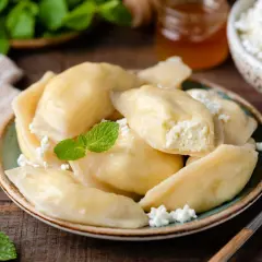Pyszne pierogi z serem na słodko, posypane twarogiem i udekorowane miętą. Idealne na deser.