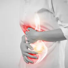 Persona con dolor de estómago, buscando remedios para los ardores. La zona afectada se ilumina en rojo y amarillo.