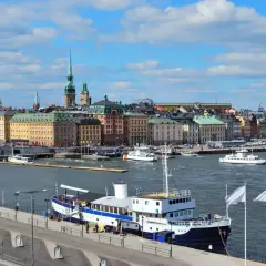 Widok na port w Sztokholmie, gdzie cumuje prom. W tle kolorowe kamienice i wieże.