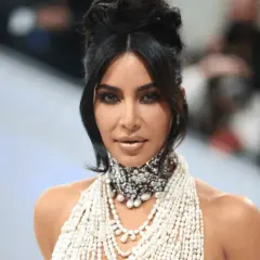 Kim Kardashian na Met Gali w olśniewającej kreacji z pereł i kryształów, z charakterystyczną fryzurą i makijażem.