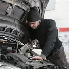 Mechanik sprawdza silnik, szukając przyczyny awarii. Zastanawiasz się, ile kosztuje naprawa silnika w samochodzie?