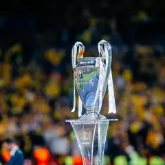 Trofeum Ligi Mistrzów na tle rozmazanej publiczności. Wartość awansu do Ligi Mistrzów jest ogromna.