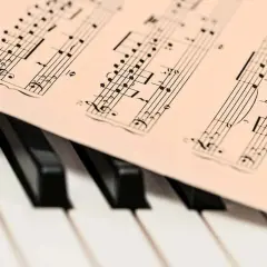 Partition de musique posée sur un clavier de piano. Les notes semblent prêtes à être jouées, une mélodie en attente de la touche de la diese.