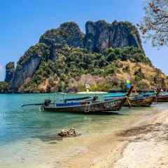 Tajlandia wakacje all inclusive: łodzie na plaży z widokiem na skaliste wyspy. Idealne miejsce na relaks.