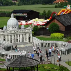 Miniaturowy park z modelem Bazyliki św. Piotra i placem Berniniego. W tle zjeżdżalnia i budynki. Sprawdź inwałd park cennik.