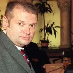 Krzysztof Rutkowski młody, w szarym garniturze i czerwono-niebieskim krawacie, patrzy w obiektyw.
