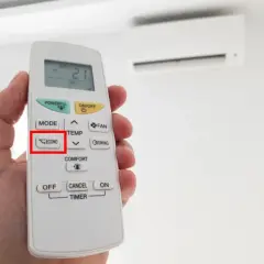 Mano sosteniendo un control remoto de aire acondicionado, con el botón "ECONO" resaltado. Activa el modo eco para ahorrar energía.
