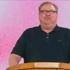 Rick Warren, mit Brille und Bart, spricht hinter einem Holzpult. Der Hintergrund ist pink.