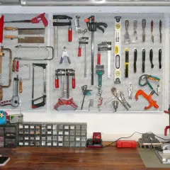 Parete porta attrezzi con pallet, organizzata con martelli, seghe, pinze e altri strumenti.