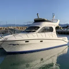 Yacht Intermare 30 ormeggiato in porto, con riflessi sull'acqua calma. Montagne sullo sfondo.