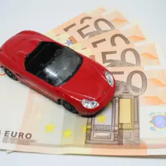 Macchinina rossa su banconote da 50 euro, simbolo di un possibile pignoramento auto cointestata.