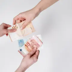 Dwie ręce przekazują sobie banknoty euro. To popularna waluta we Włoszech, używana do codziennych transakcji.